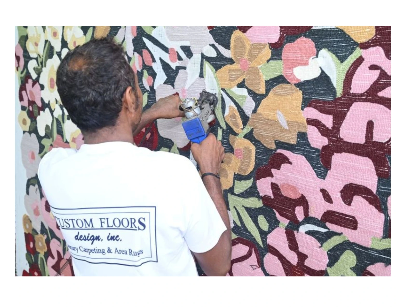 Artisan creating a colorful floral rug with a tufting tool